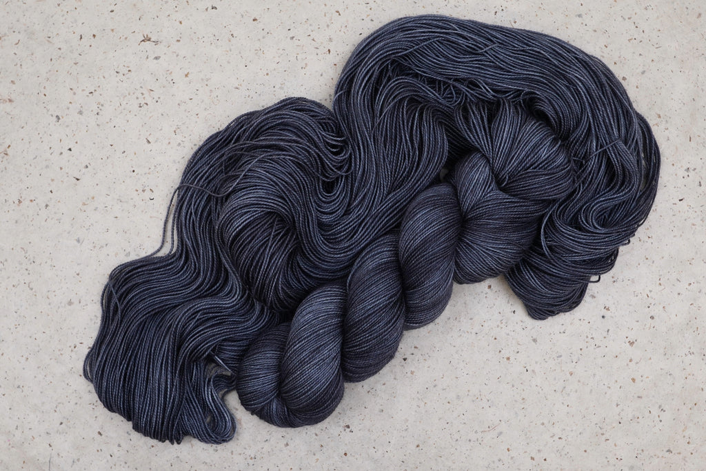 Wild Woollys Obsidian Nights yarn, an unwound skein in deep charcoal grey