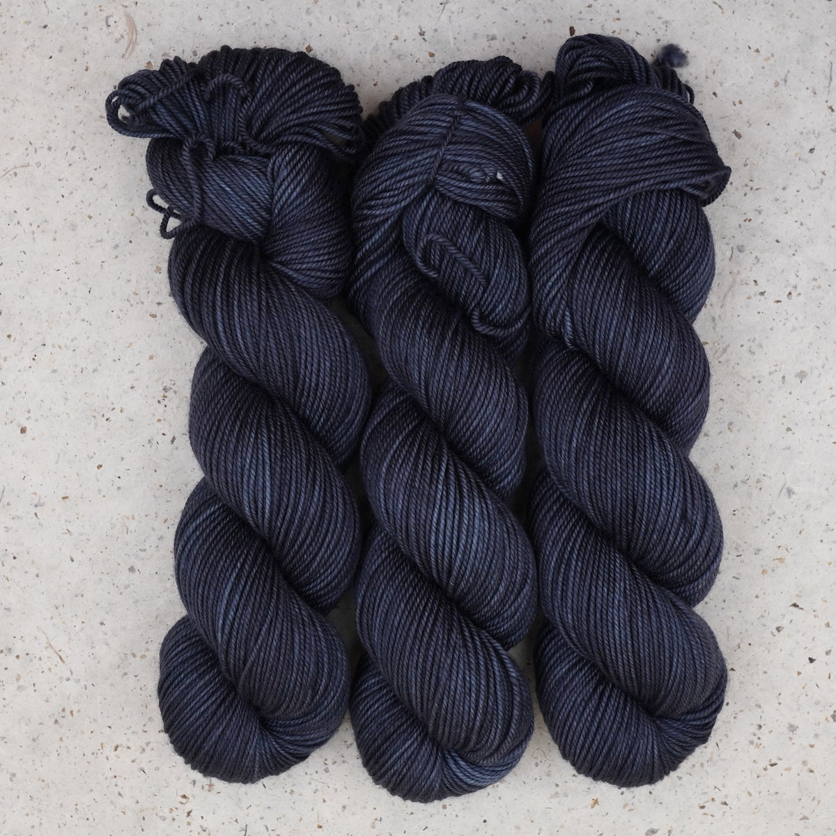 Wild Woollys Obsidian Nights DK yarn, three skeins in near-black navy and charcoal