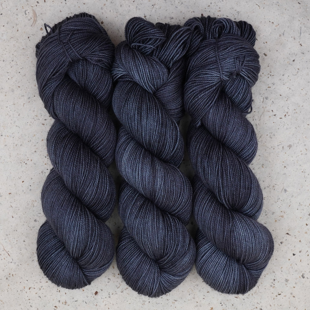 Hilo Obsidian Nights Fingering de Wild Woollys — tres madejas en azul marino casi negro y gris carbón