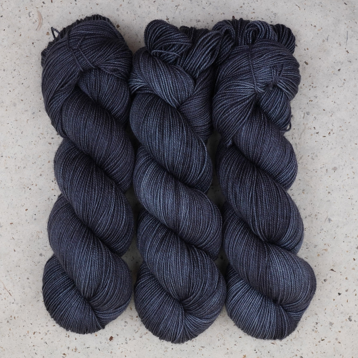 Hilo Obsidian Nights Fingering de Wild Woollys — tres madejas en azul marino casi negro y gris carbón