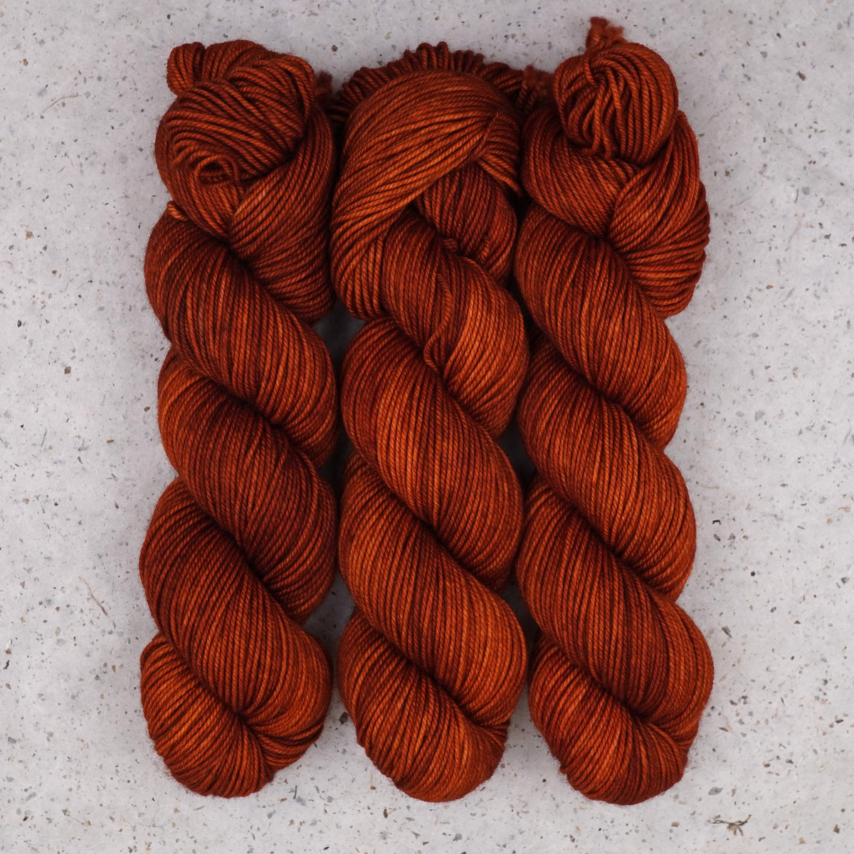 Wild Woollys Penny Laine DK yarn, three skeins in rich rust orange and copper