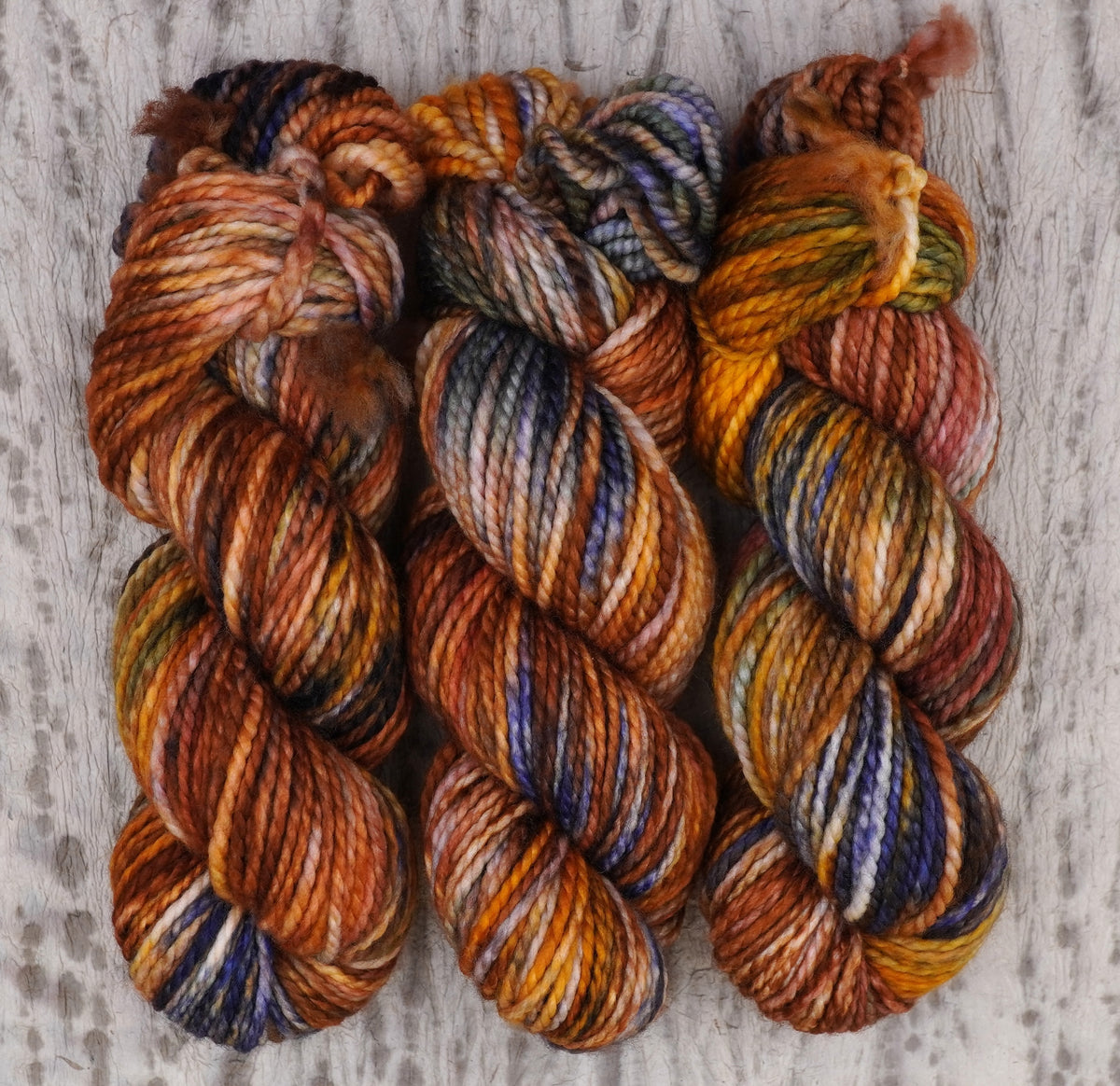 Hilo Smashing Gourds Bulky de Wild Woollys — tres madejas en naranja calabaza, dorado y cobre con motas