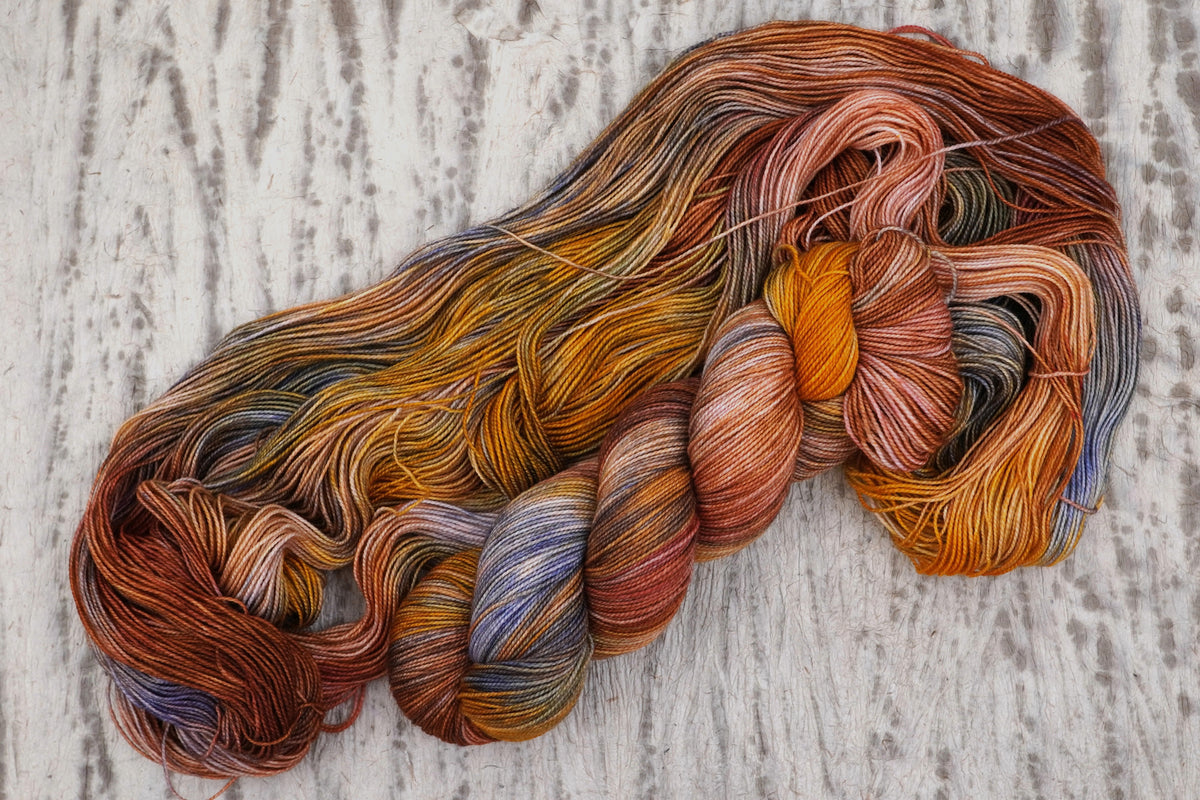 Wild Woollys Smashing Gourds yarn, an unwound skein showing pumpkin orange, gold, and copper with speckles