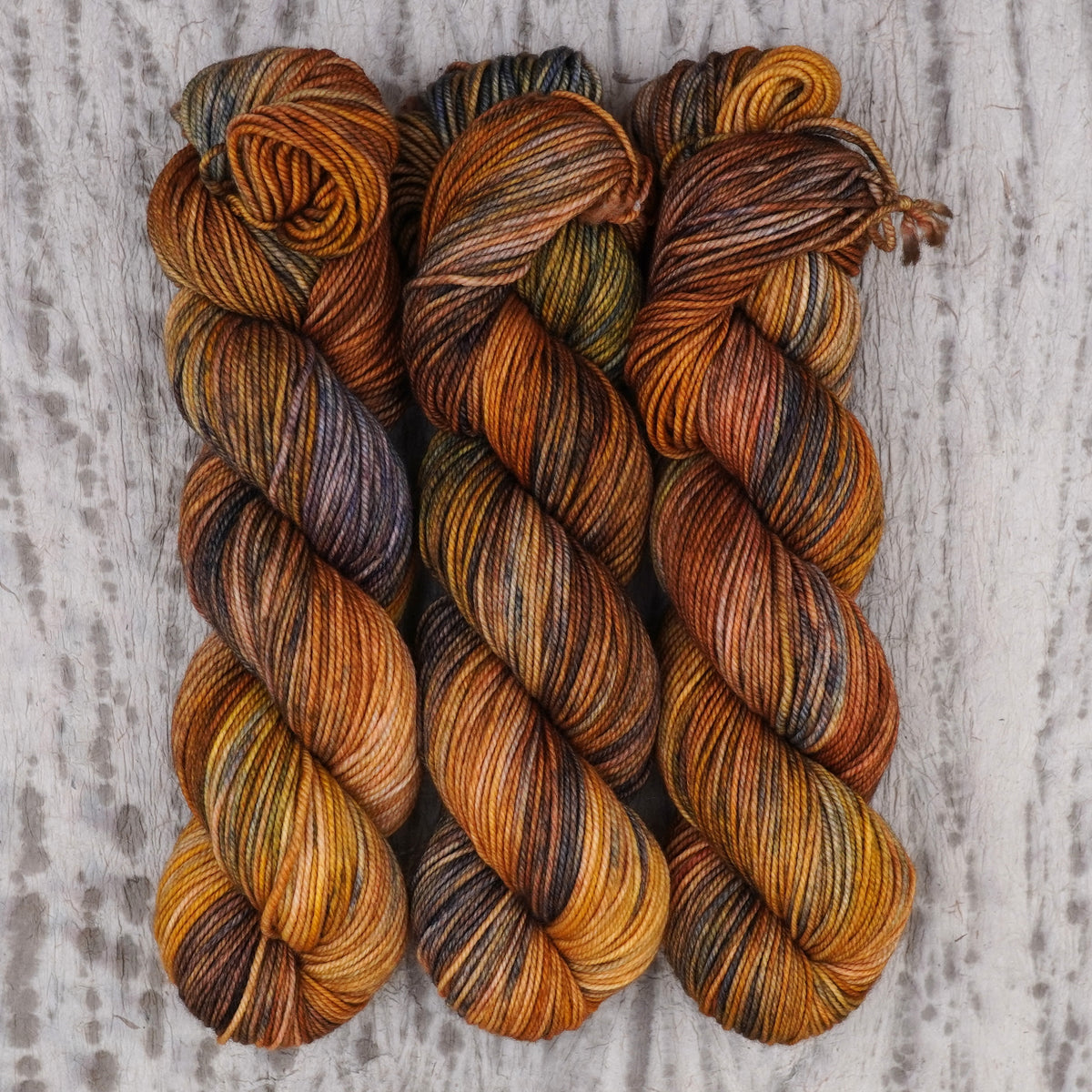 Hilo Smashing Gourds DK de Wild Woollys — tres madejas en naranja calabaza, dorado y cobre con motas