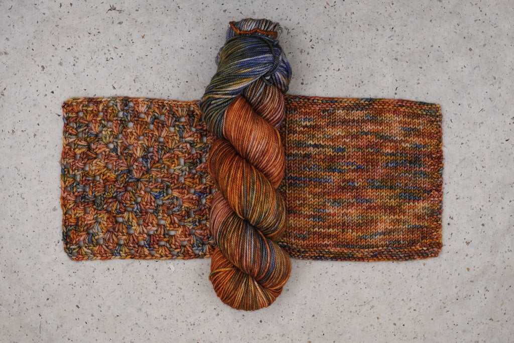 Wild Woollys Smashing Gourds yarn in rust orange, gold and blue, one skein with knitted and crocheted swatches