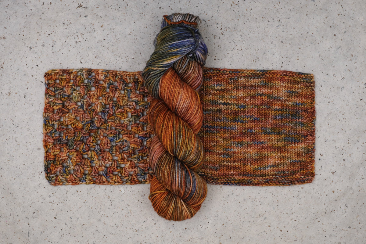 Wild Woollys Smashing Gourds yarn in rust orange, gold and blue, one skein with knitted and crocheted swatches