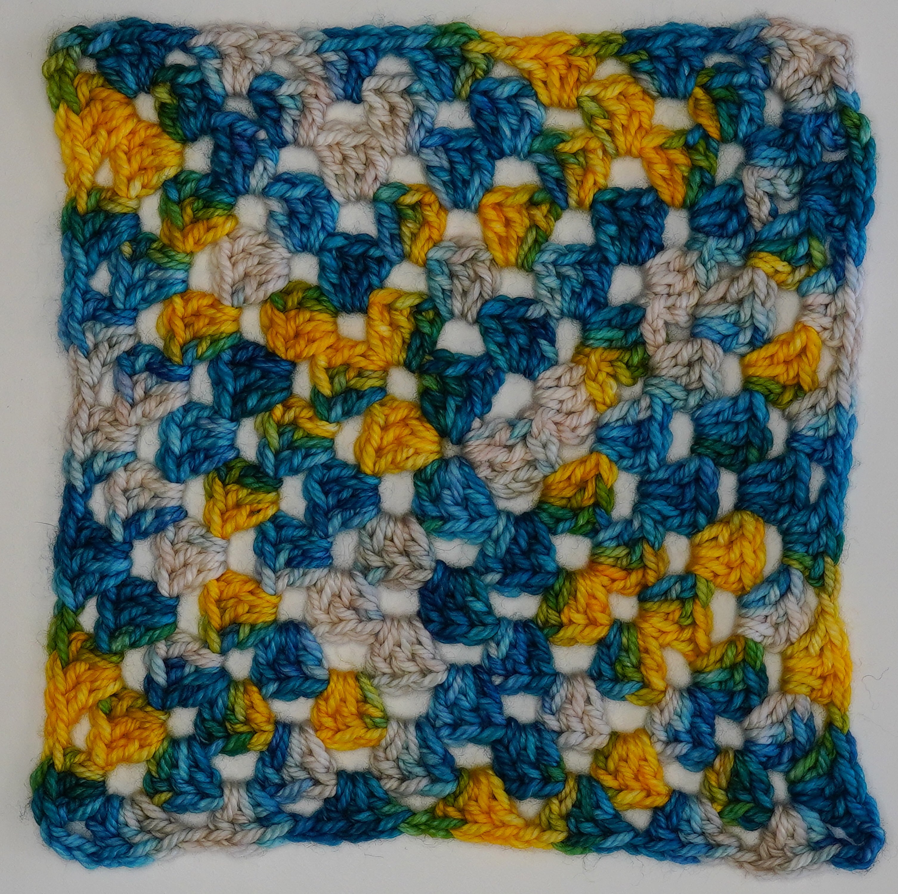 Wild Woollys Tropical Escape yarn swatch with blue, yellow, and white granny square crochet pattern