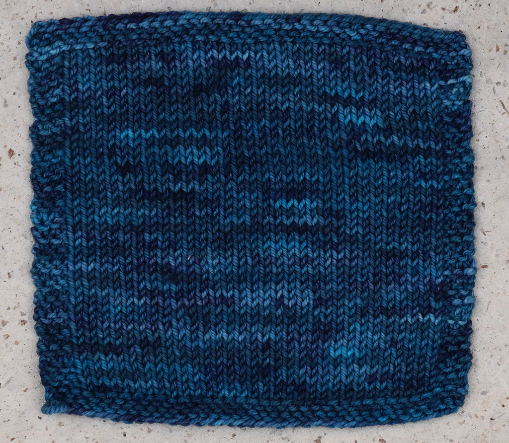 A knitted swatch of Wild Woollys Teal of Fortune yarn in deep teal and blue
