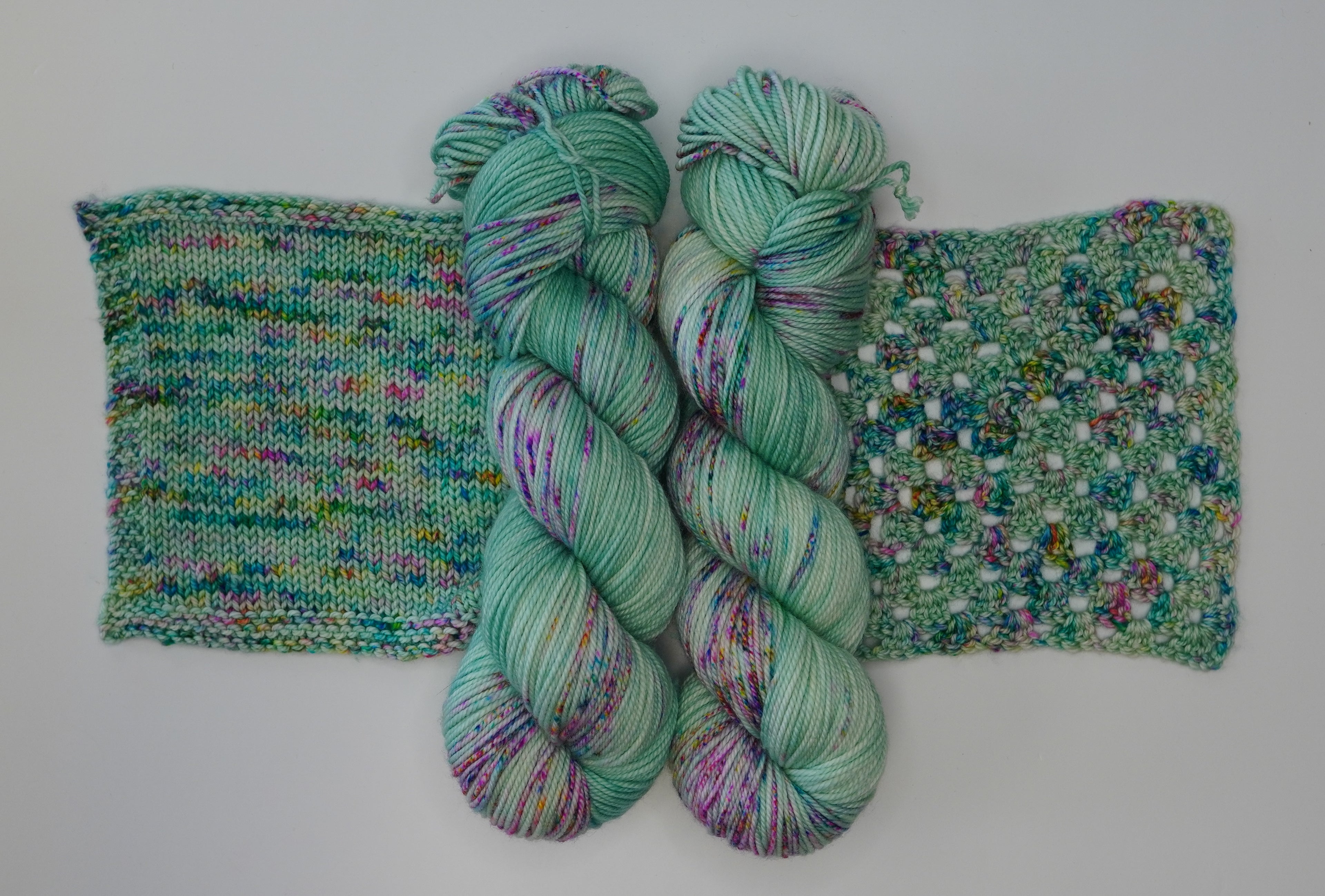 Two skeins of Wild Woollys Undersea Garden yarn with knitted and crocheted swatches