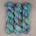 Fil Undersea Garden Fingering de Wild Woollys — trois écheveaux aux tons vert menthe doux avec des mouchetures violettes et bleues
