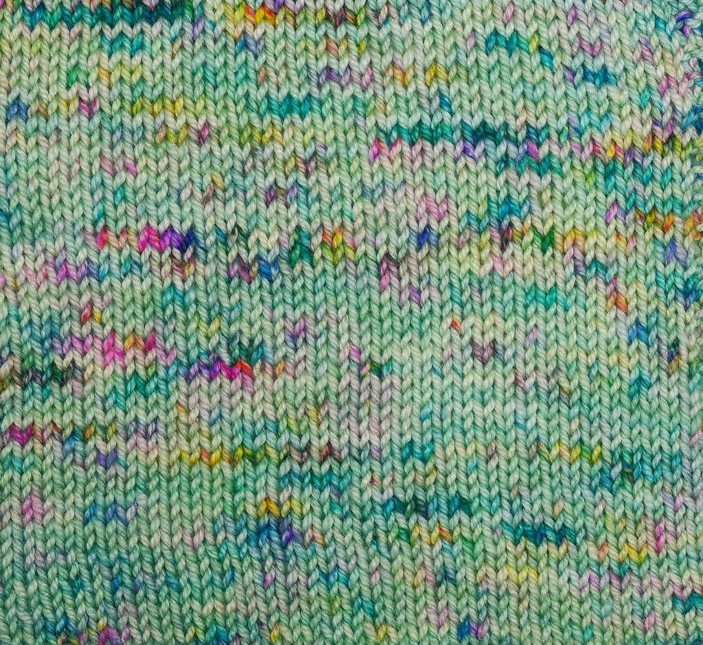 Close-up of a knitted fabric with a multicolor pattern on a light green background