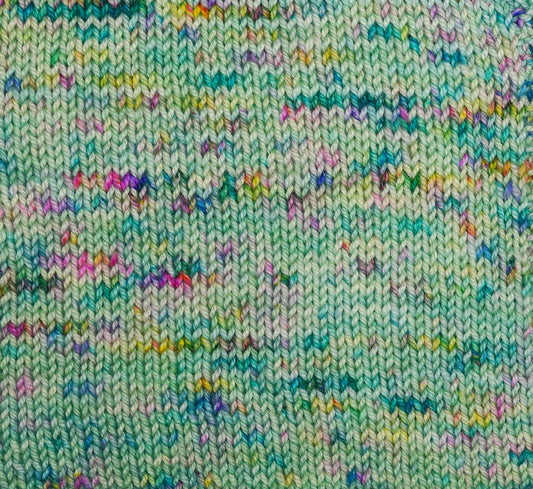 Close-up of a knitted fabric with a multicolor pattern on a light green background