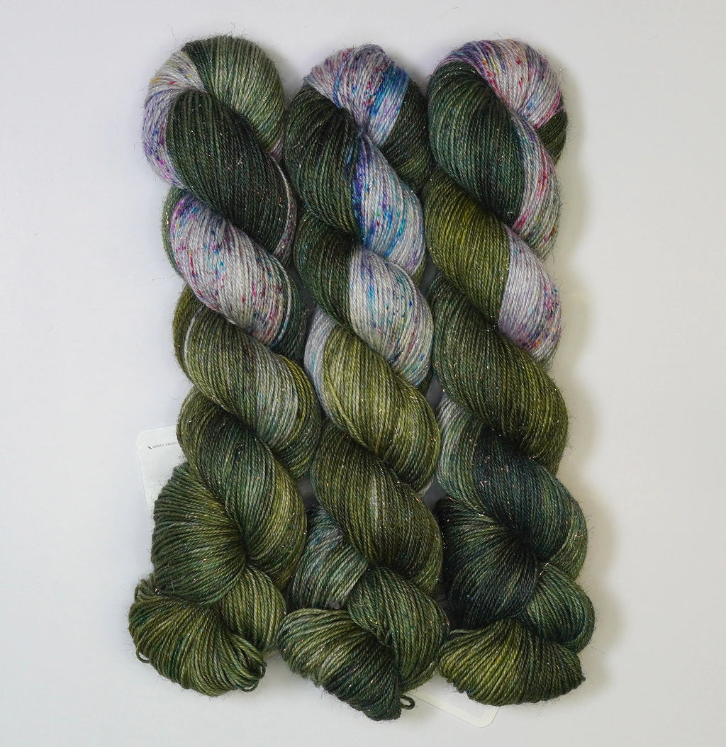 Wild Woollys Vintage Christmas Tree yarn, three skeins of dark green, light green, and white yarn