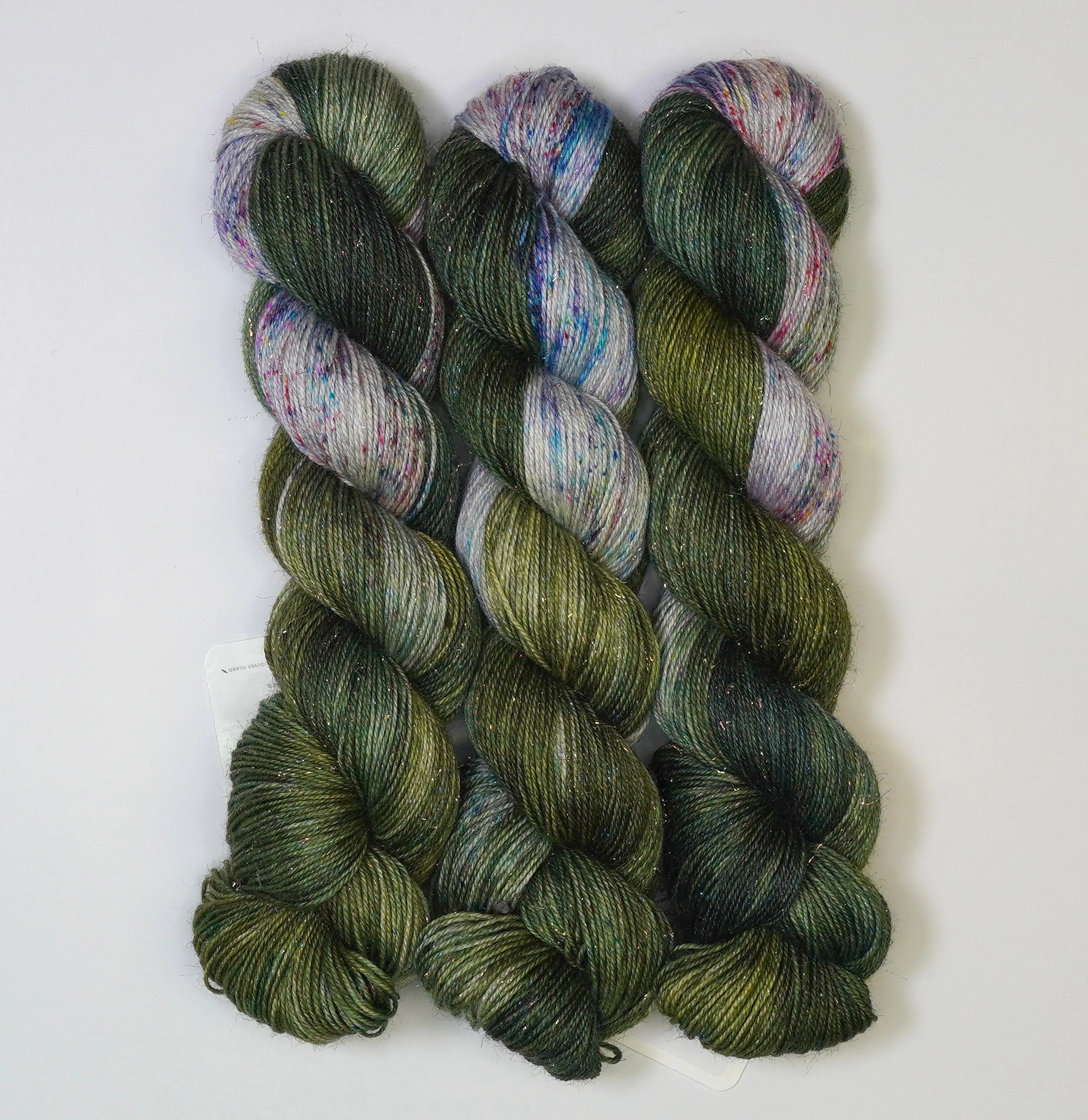 Wild Woollys Vintage Christmas Tree yarn, three skeins of dark green, light green, and white yarn
