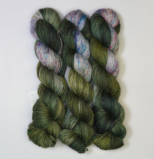 Wild Woollys Vintage Christmas Tree yarn, three skeins of dark green, light green, and white yarn