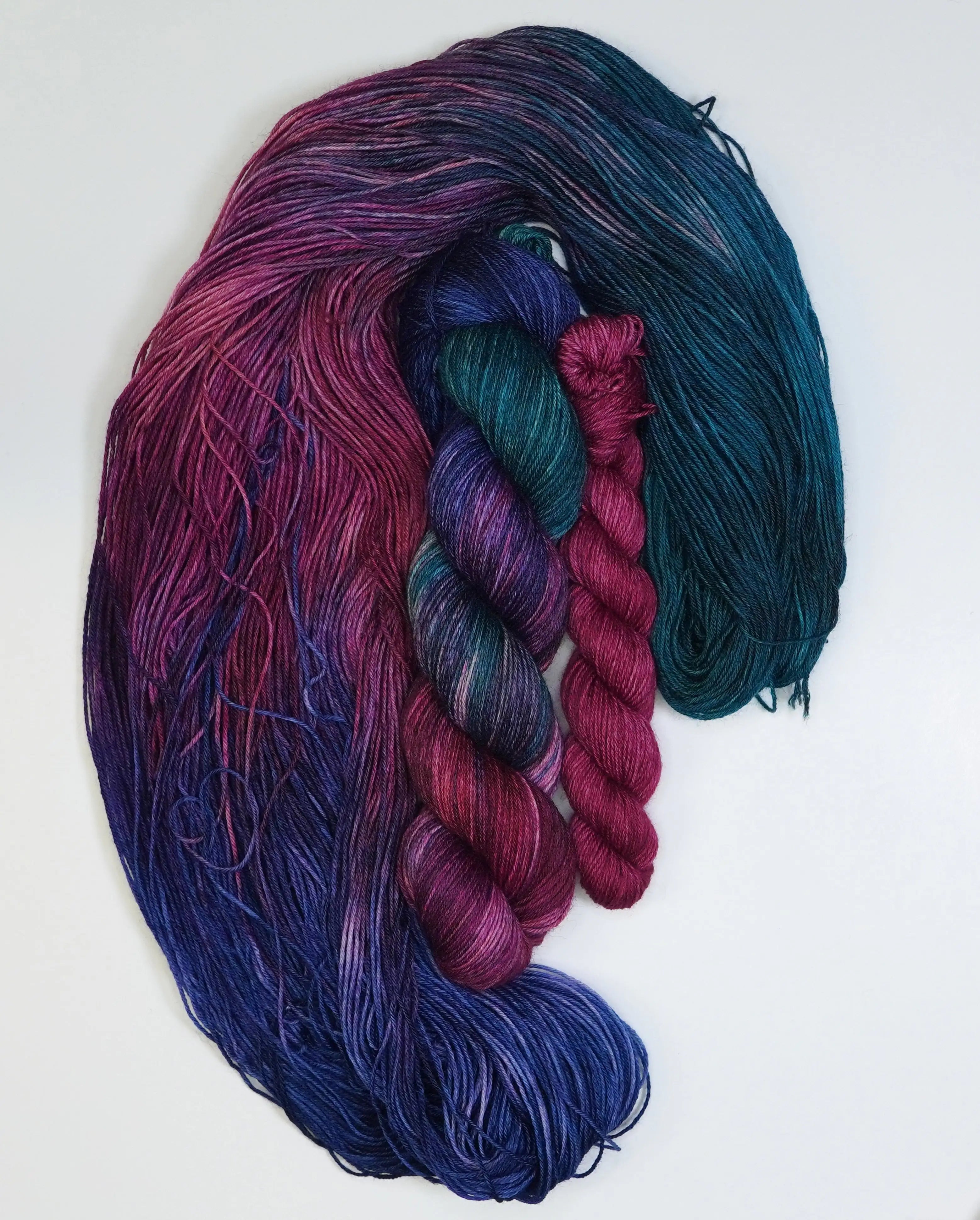 Wild Woollys Winter Aurora Fingering Sock Set with four skeins of yarn in shades of purple, blue, and teal