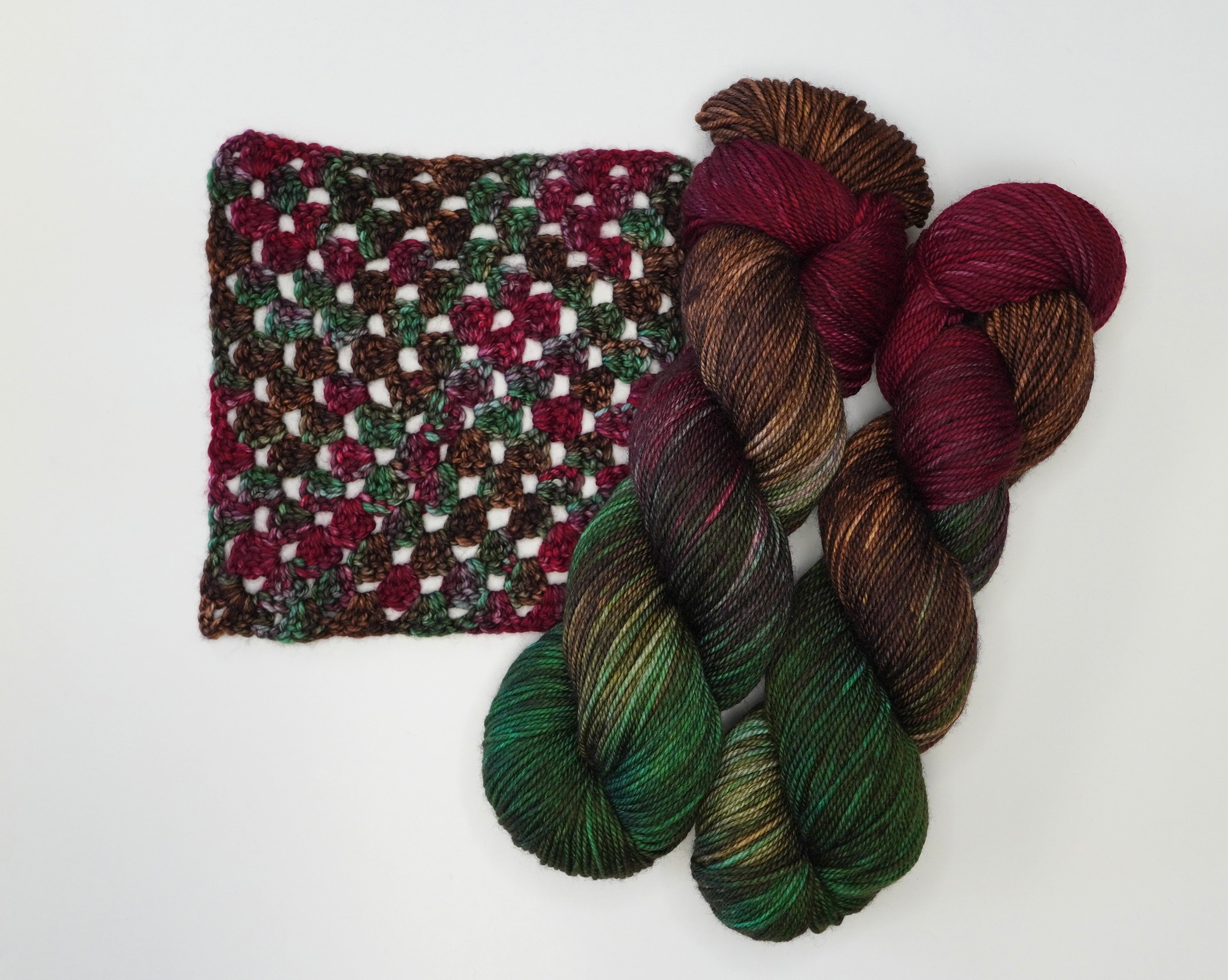 Woodland Christmas yarn by Wild Woollys, with a crocheted swatch and three skeins of yarn