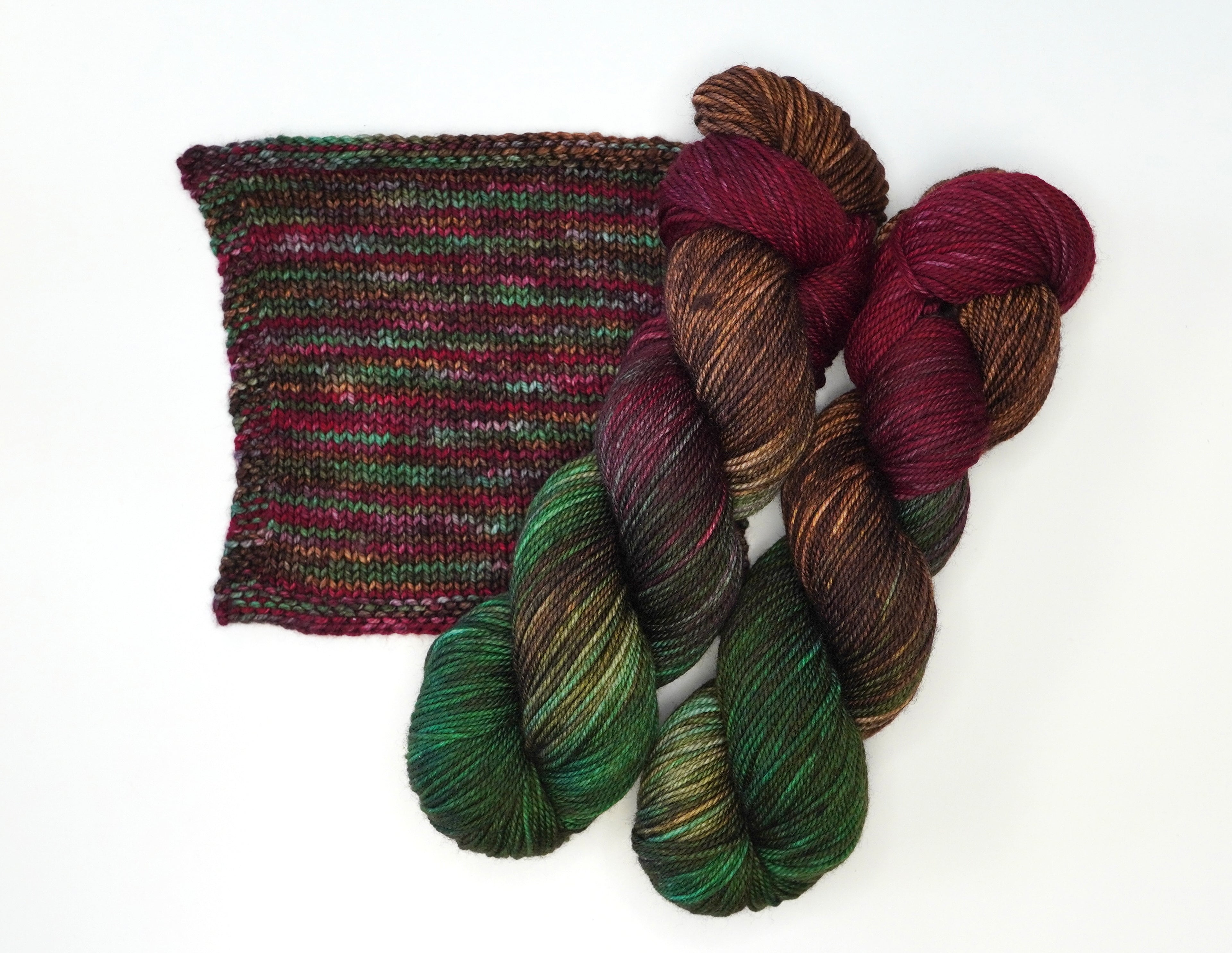Wild Woollys Woodland Christmas yarn in red, green, and brown with a knitted swatch