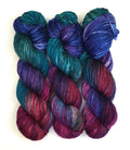 Three skeins of multicolored yarn in shades of blue, purple, and red on a white background.