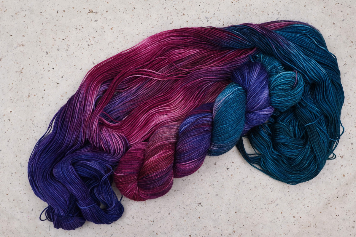 Wild Woollys Winter Aurora yarn, an unwound skein showing navy, purple, magenta, and teal