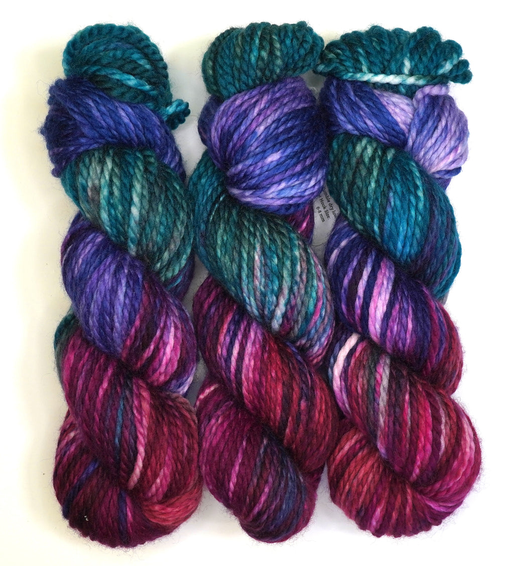 Set of colorful yarn skeins in purple, blue, and red on a white background