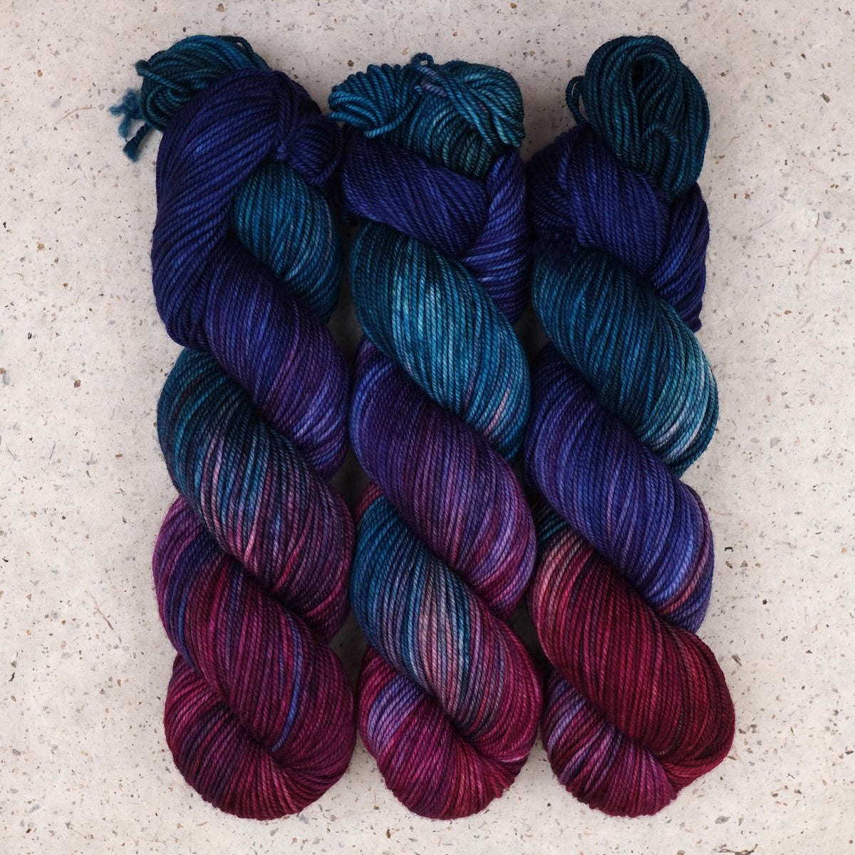 Wild Woollys Winter Aurora DK yarn, three skeins in navy, purple, magenta, and teal