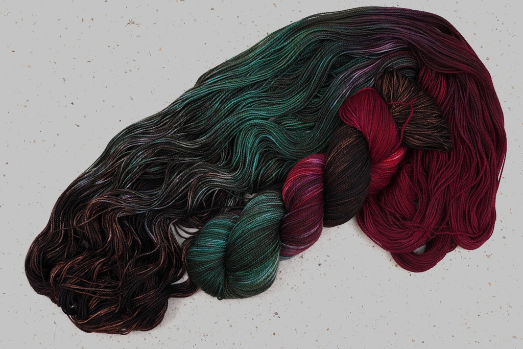 Wild Woollys Woodland Christmas yarn, an unwound skein showing deep forest green, crimson, and near-black