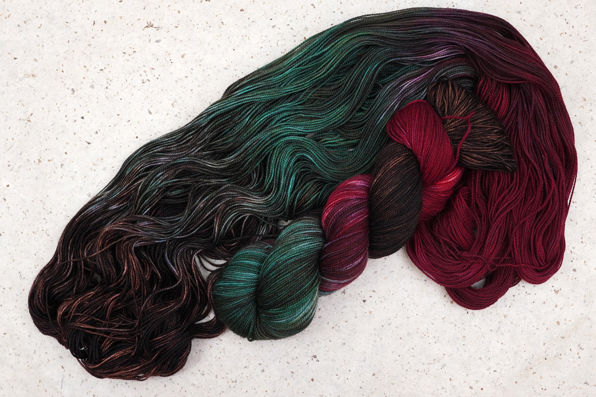 Wild Woollys Woodland Christmas yarn, an unwound skein showing deep forest green, crimson, and near-black