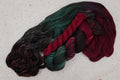 Wild Woollys Woodland Christmas sock set, an unwound skein in deep forest green, crimson, and near-black with a contrasting crimson mini-skein