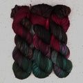 Wild Woollys Woodland Christmas Fingering yarn, three skeins in deep forest green, crimson, and near-black