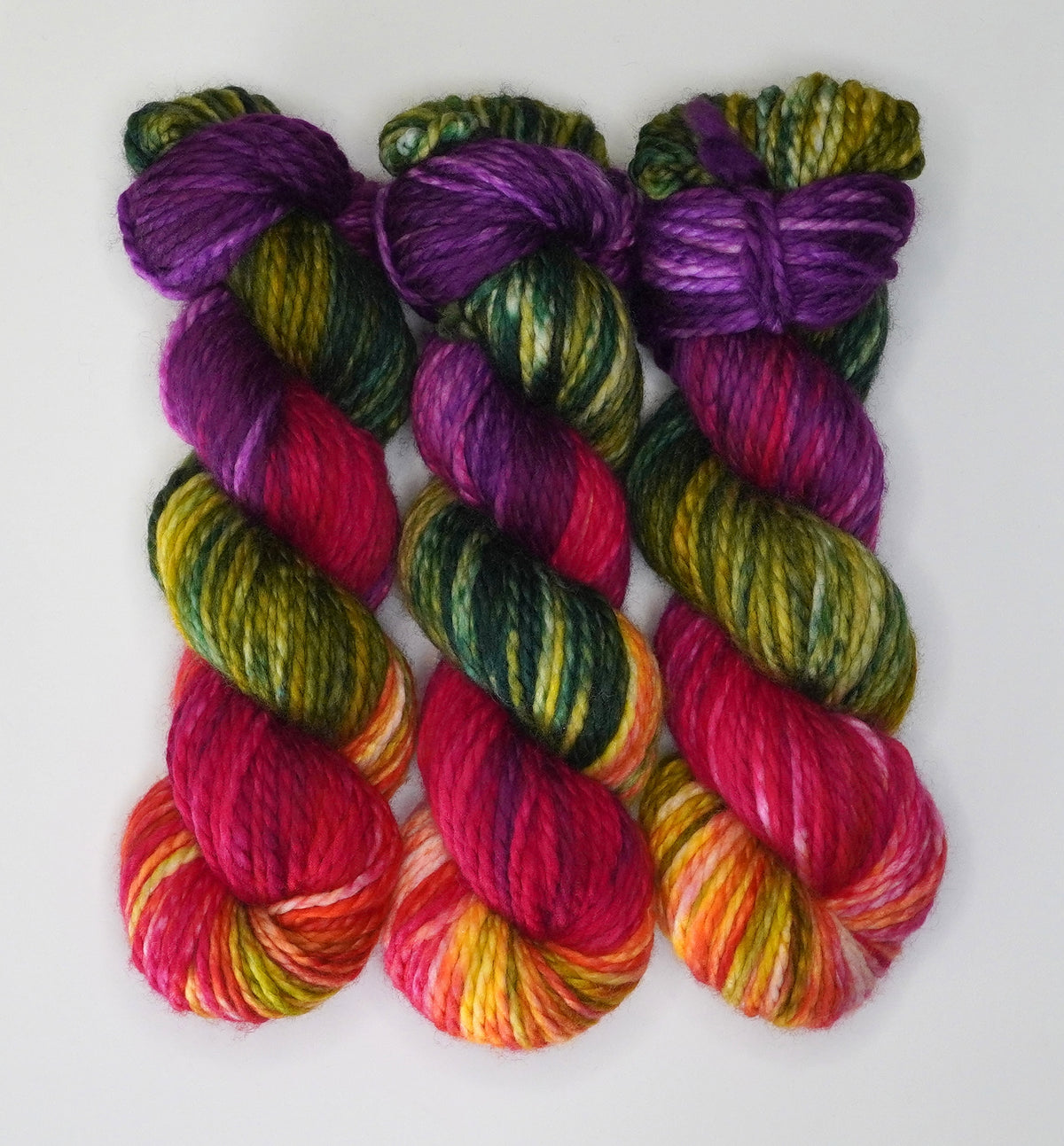 Wild Woollys Summer Berry bulky yarn, three skeins with purple, green, red, and yellow colors